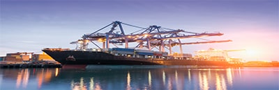 Cargo shipping yard with cargo ship and overhead cranes